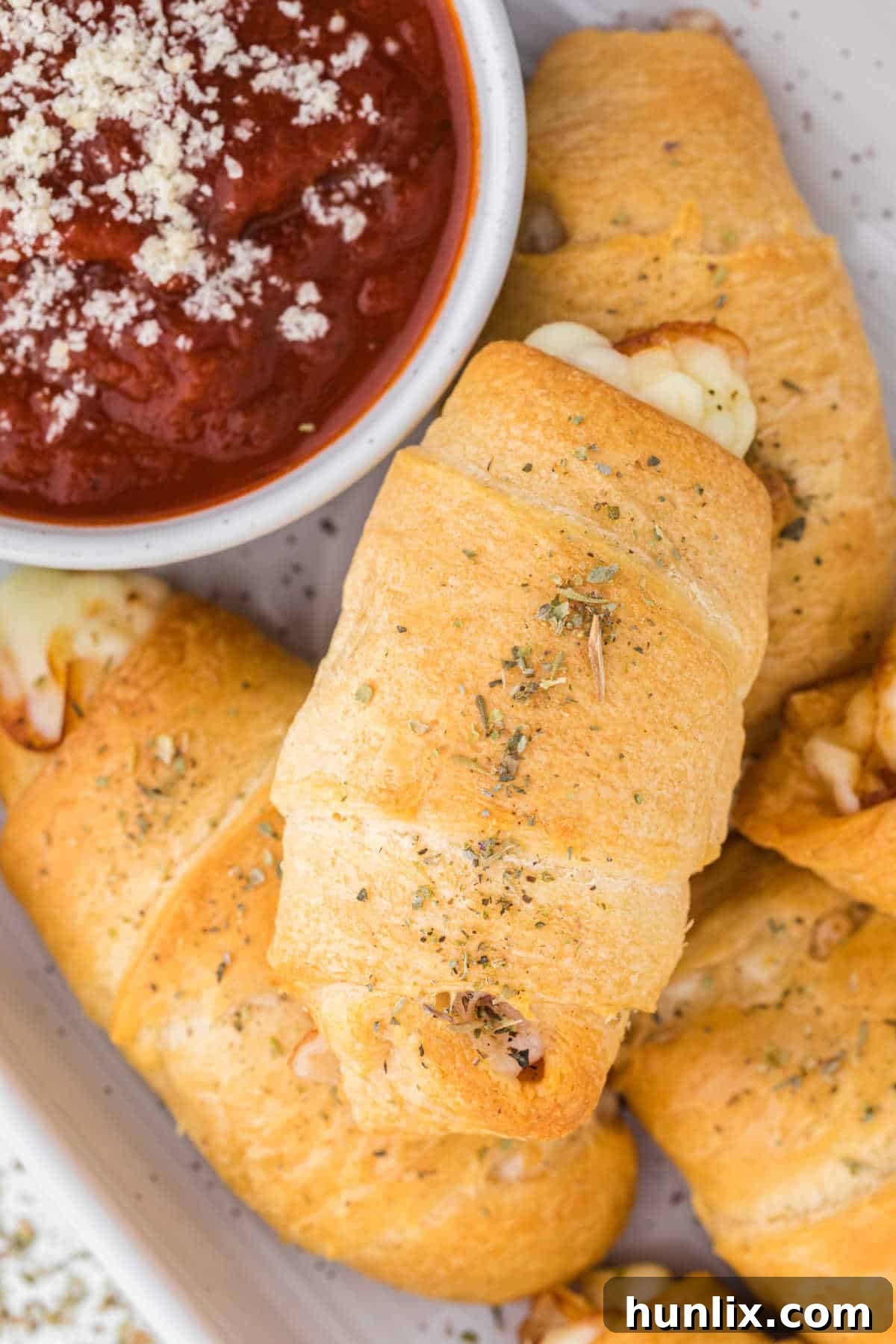 Cooked pizza rolls arranged beautifully on a white platter, with a bowl of pizza sauce for dipping.