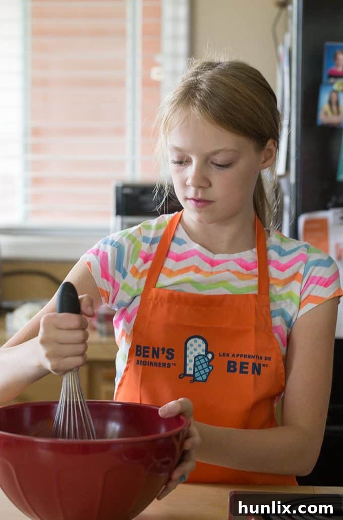 Close-up of a child's hands mixing ground beef and rice for meatballs, emphasizing the hands-on fun of cooking.