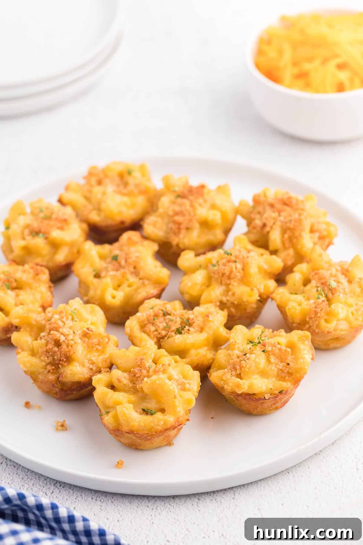A single mac and cheese cup on a white plate, garnished with fresh parsley.