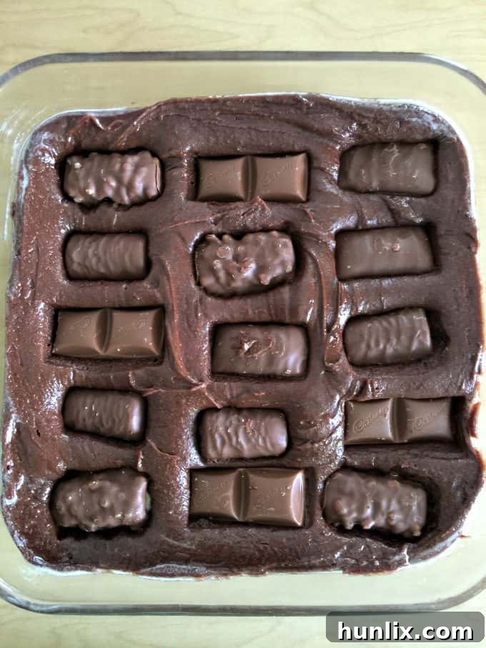 Mini Halloween chocolate bars pressed into rich brownie batter, ready for baking.