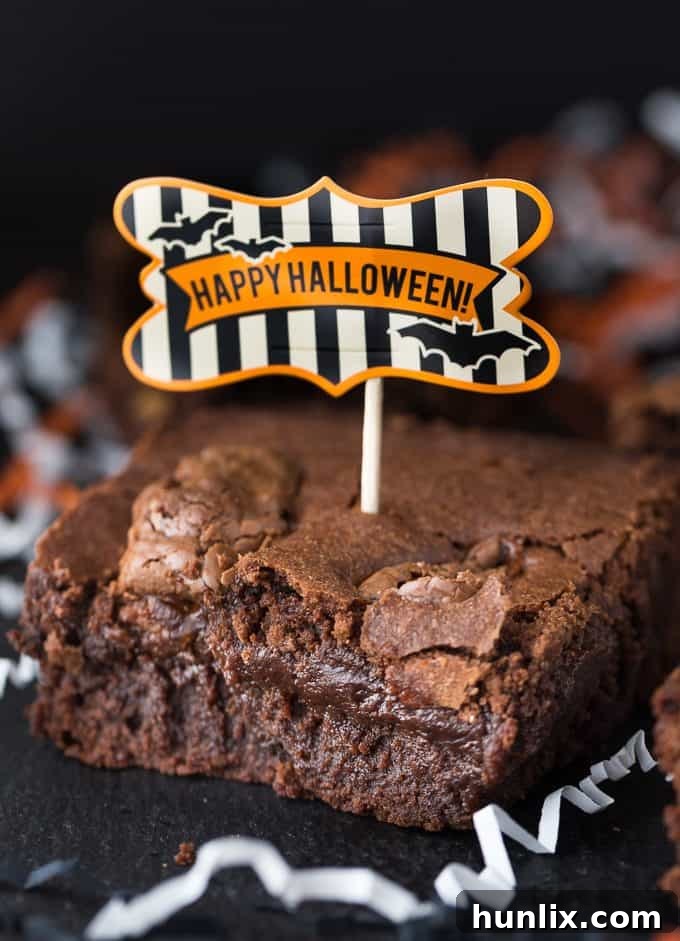 Close-up of a cut Halloween brownie revealing gooey, melted candy bar pieces inside.