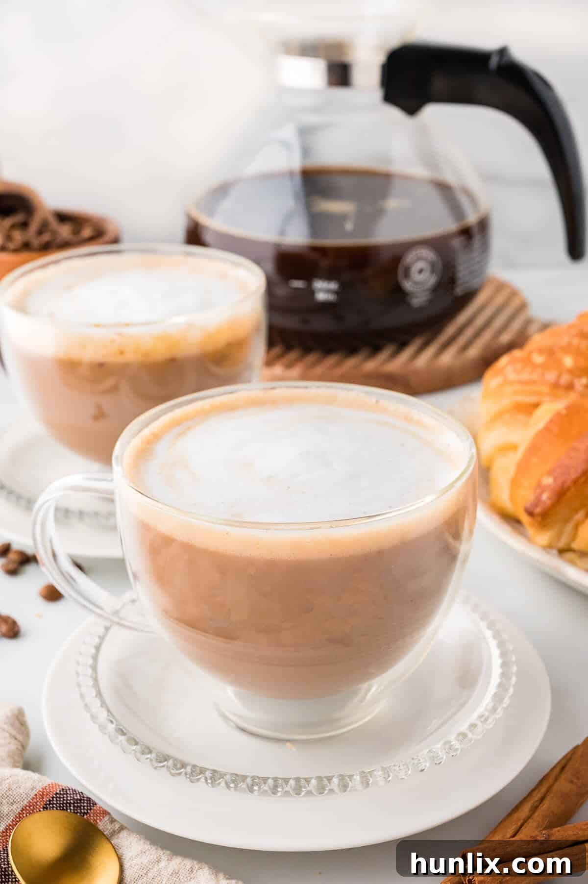 A cinnamon cappuccino artfully presented on a plate with a decorative spoon, highlighting its creamy texture and inviting appeal.