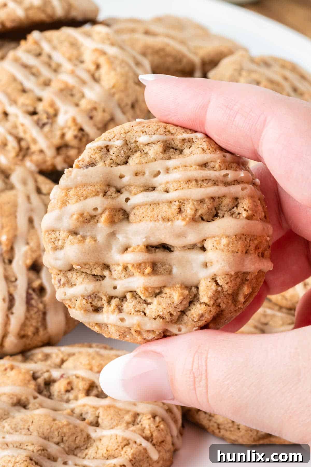A hand holding a perfectly baked and glazed brown sugar cookie.