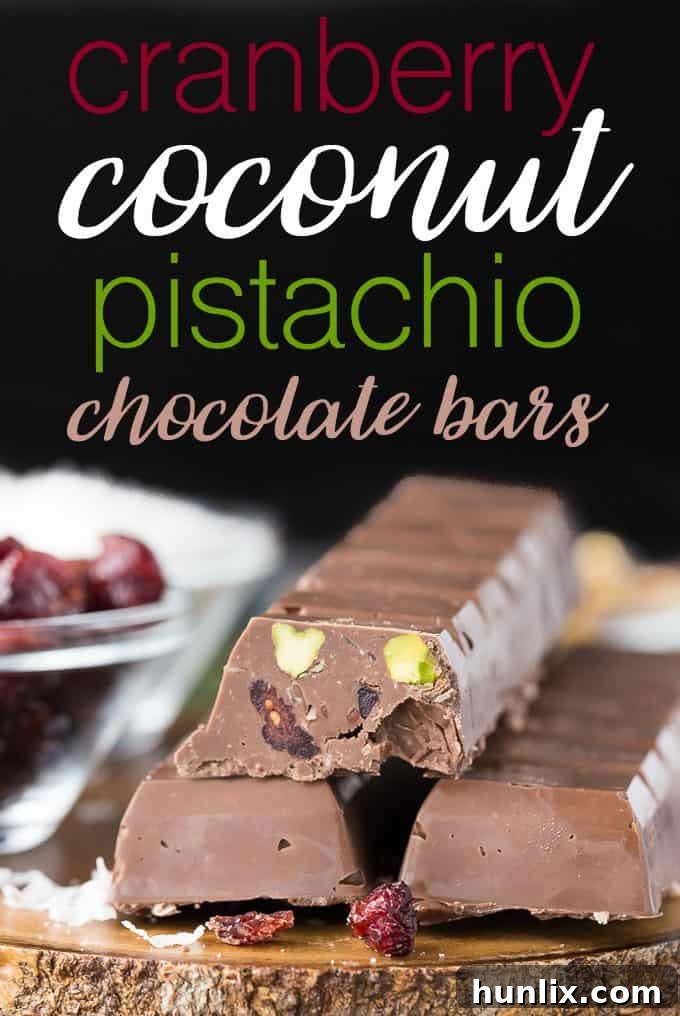 Cranberry Coconut Pistachio Chocolate Bars - The best Christmas treat! Make these delicious red and green desserts for all your loved ones this year. A close-up shot of homemade chocolate bars speckled with cranberries, coconut flakes, and green pistachios, perfectly set on a rustic wooden board, ready to be enjoyed or shared.