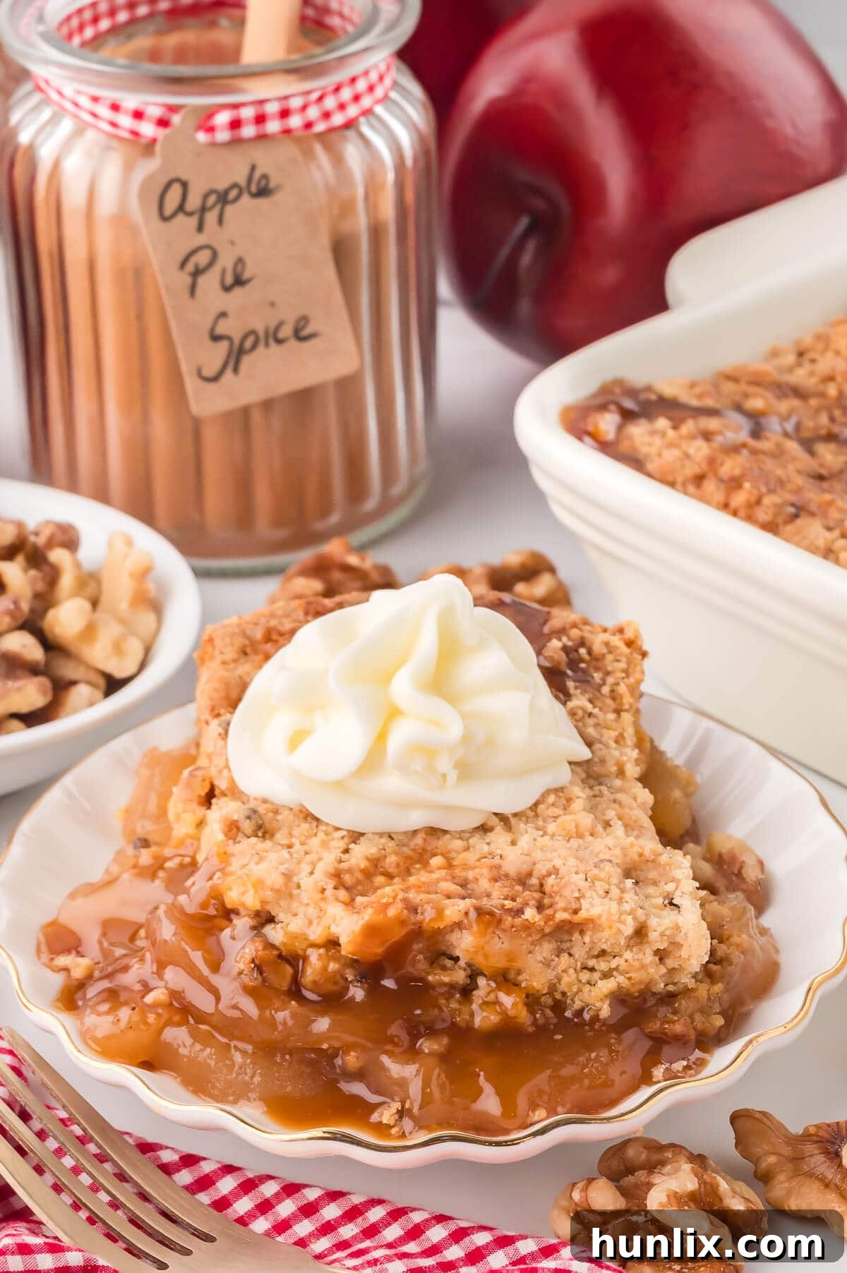 A perfectly portioned slice of golden Apple Dump Cake, elegantly topped with a swirl of fluffy whipped cream, presented in a crisp white bowl.