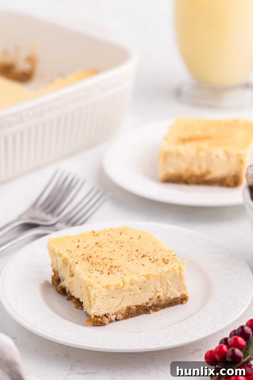 An eggnog cheesecake bar on a white plate, showcasing its creamy texture and festive appeal.
