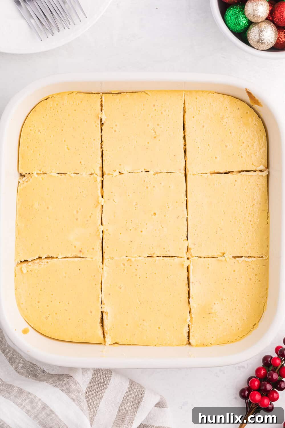 Eggnog cheesecake bars in a casserole pan, perfectly cut into squares, ready to be served.
