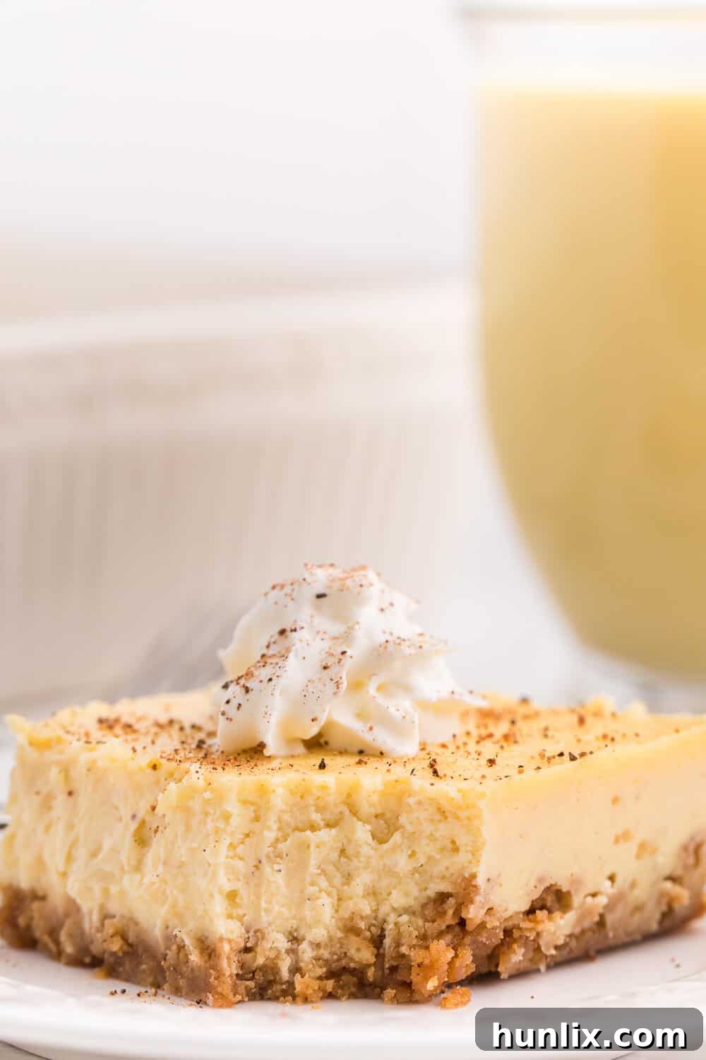 A delicious piece of eggnog cheesecake bar with a bite taken from the end, revealing its rich layers.