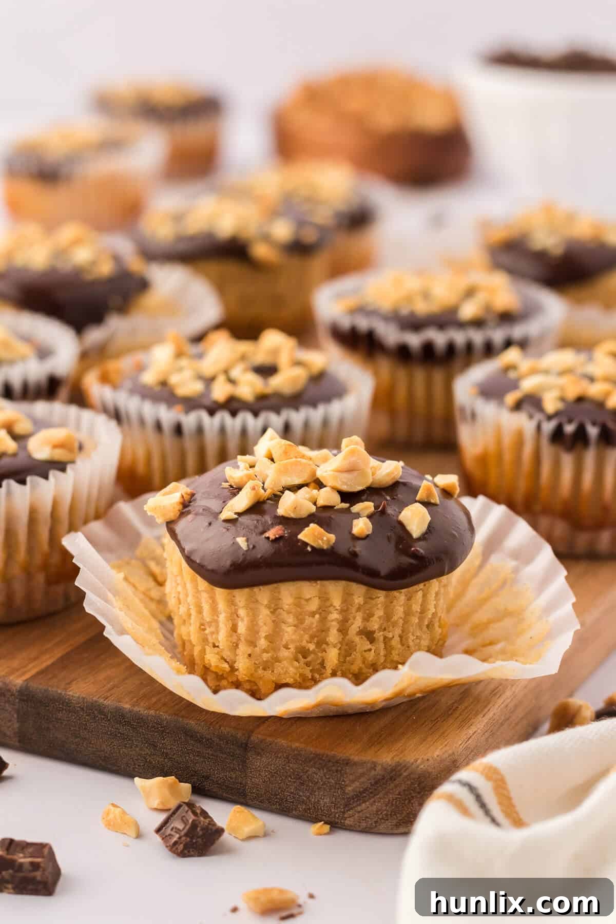 A mini peanut butter cheesecake with the liner half removed, showcasing its creamy texture and rich peanut butter filling.