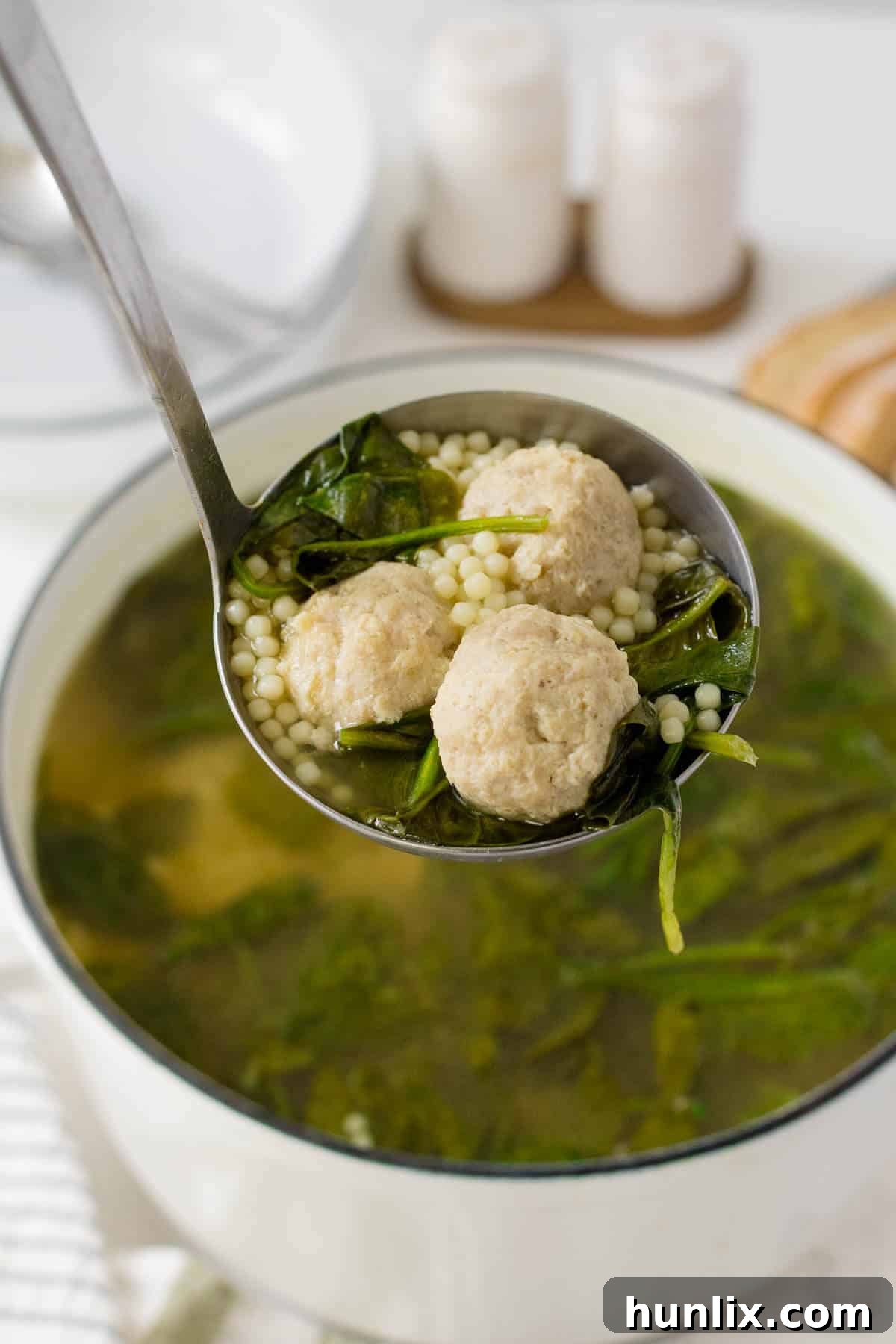 Hearty Italian Wedding Soup with Tender Chicken Meatballs 2 A ladle filled with Italian Wedding Soup featuring tender chicken meatballs and tiny pasta.