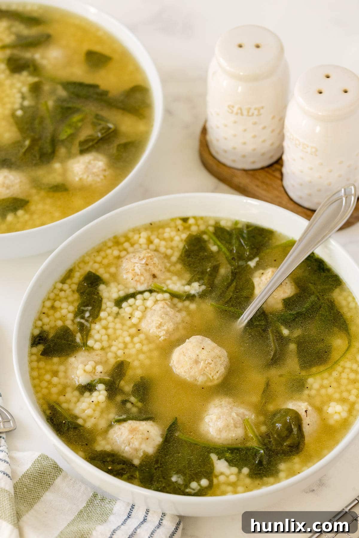 Hearty Italian Wedding Soup with Tender Chicken Meatballs 7 A bowl of Italian Wedding Soup with chicken meatballs and a spoon, ready to eat.