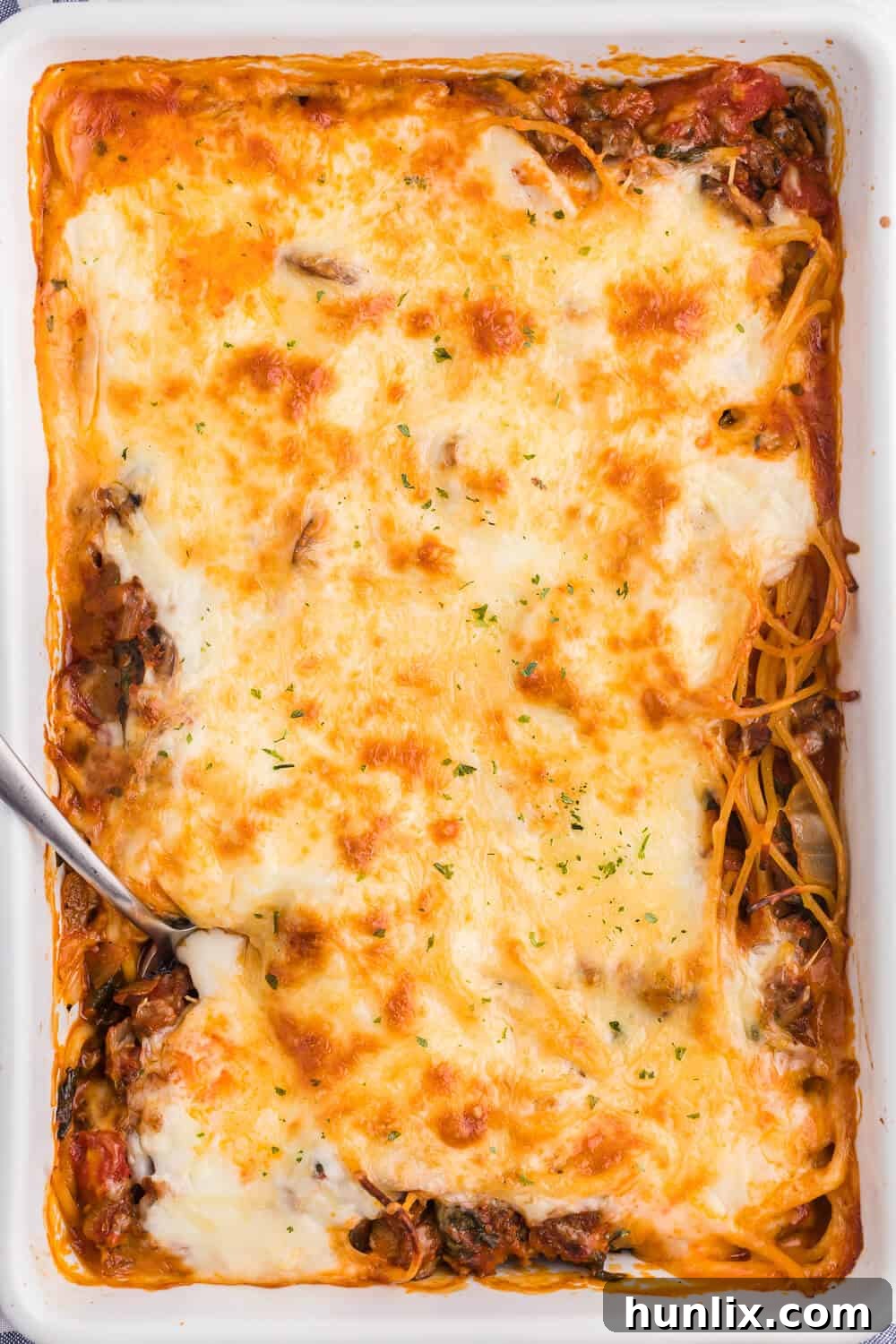 Ultimate Baked Spaghetti 3 Overhead shot of spaghetti bake in a white casserole dish, golden brown and bubbling.