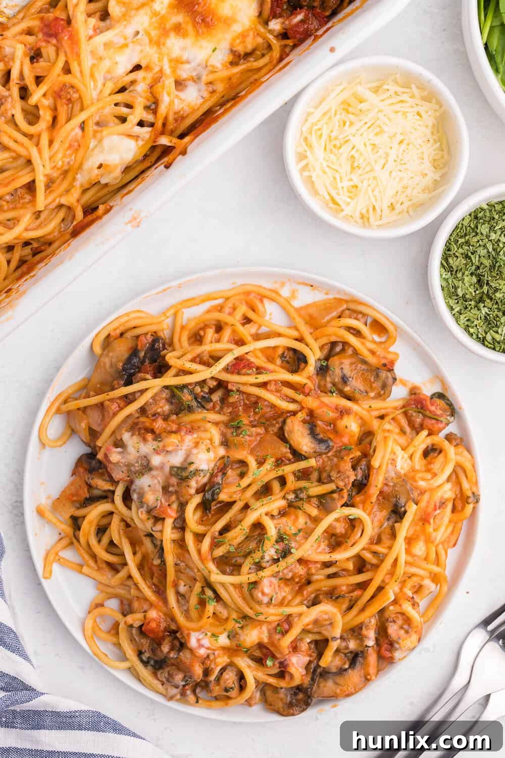 Ultimate Baked Spaghetti 5 Overhead shot of spaghetti bake served on a white plate with fresh basil garnish.