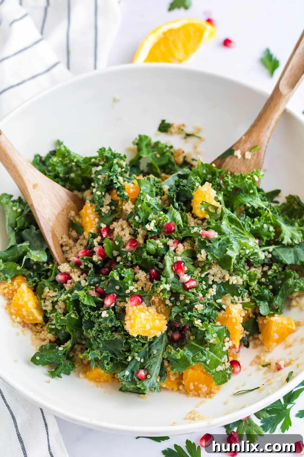 Nourishing Winter Reset Salad 4 A pristine white bowl of winter detox salad paired with elegant wooden salad tongs, ready for serving.