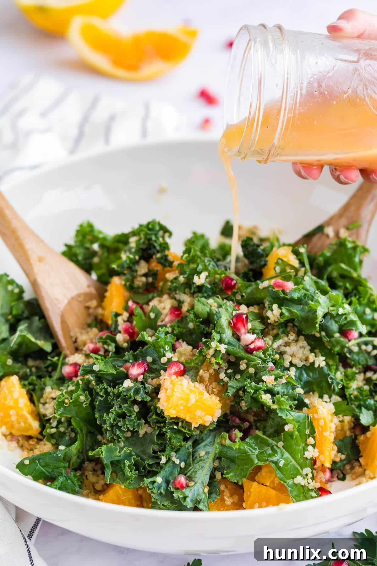 Nourishing Winter Reset Salad 5 A hand gracefully pours the vibrant orange dressing over a fresh winter detox salad.