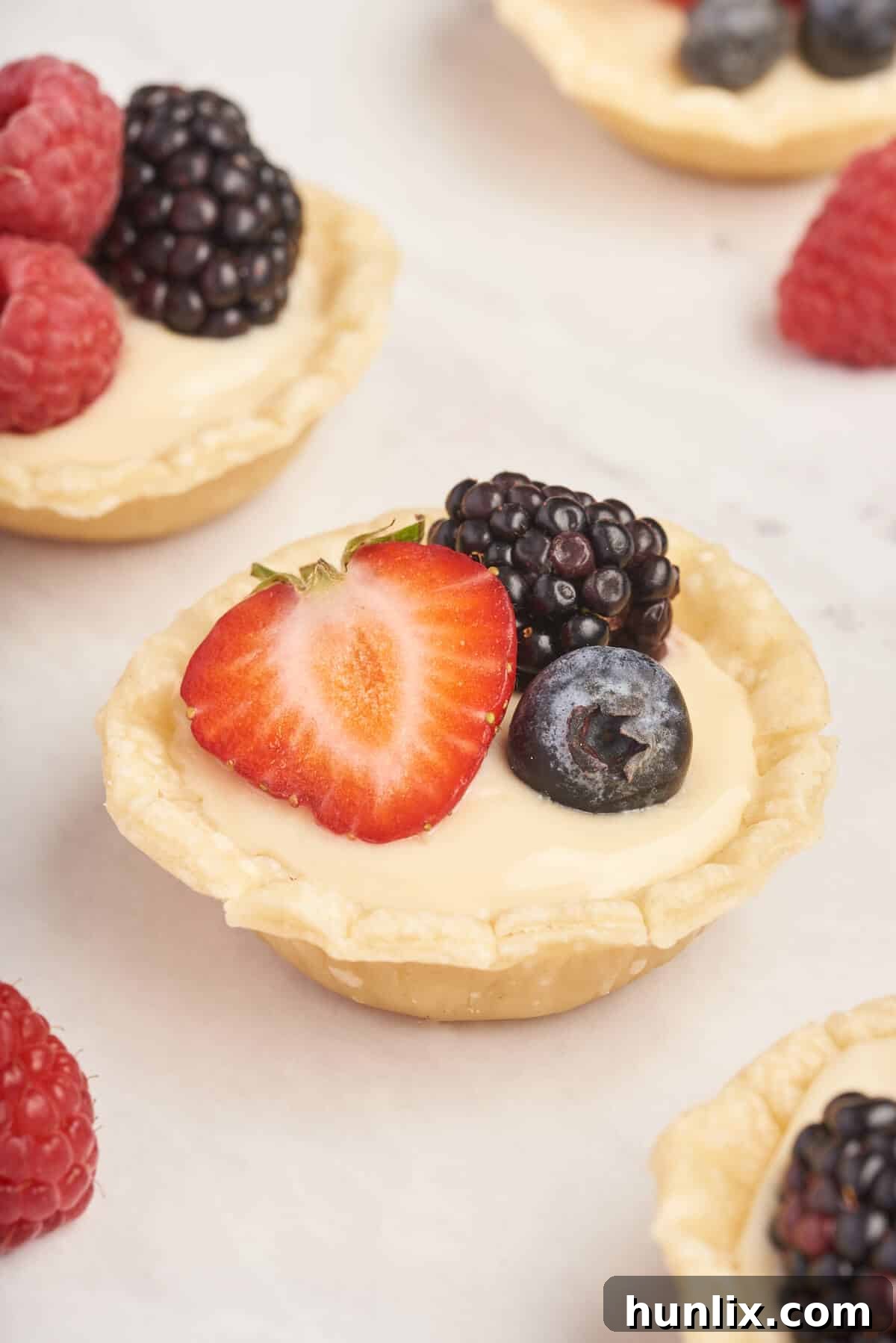 A close-up view of a single cream cheese fruit tart, showing the creamy filling and fresh berries.