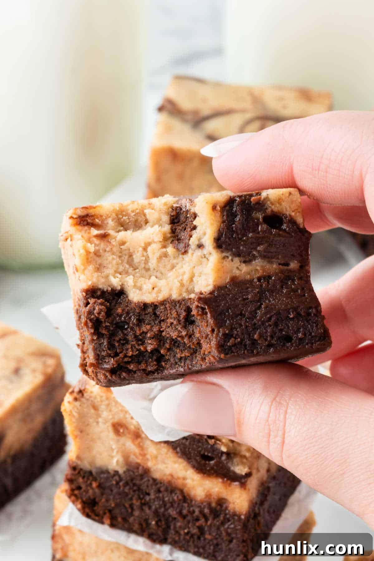 A close-up of a peanut butter cheesecake brownie with a bite taken out, showing the fudgy texture.