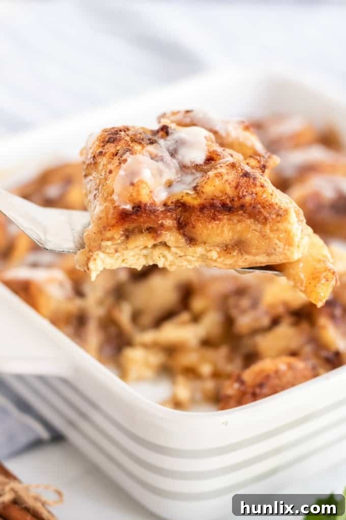 Warm Apple Cinnamon Breakfast Bake 4 A spatula lifting a slice of Apple Cinnamon Bun Breakfast Casserole.