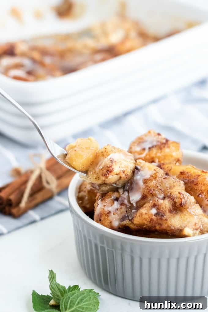 Warm Apple Cinnamon Breakfast Bake 7 A fork taking a bite of the Apple Cinnamon Bun Breakfast Casserole from a ramekin.