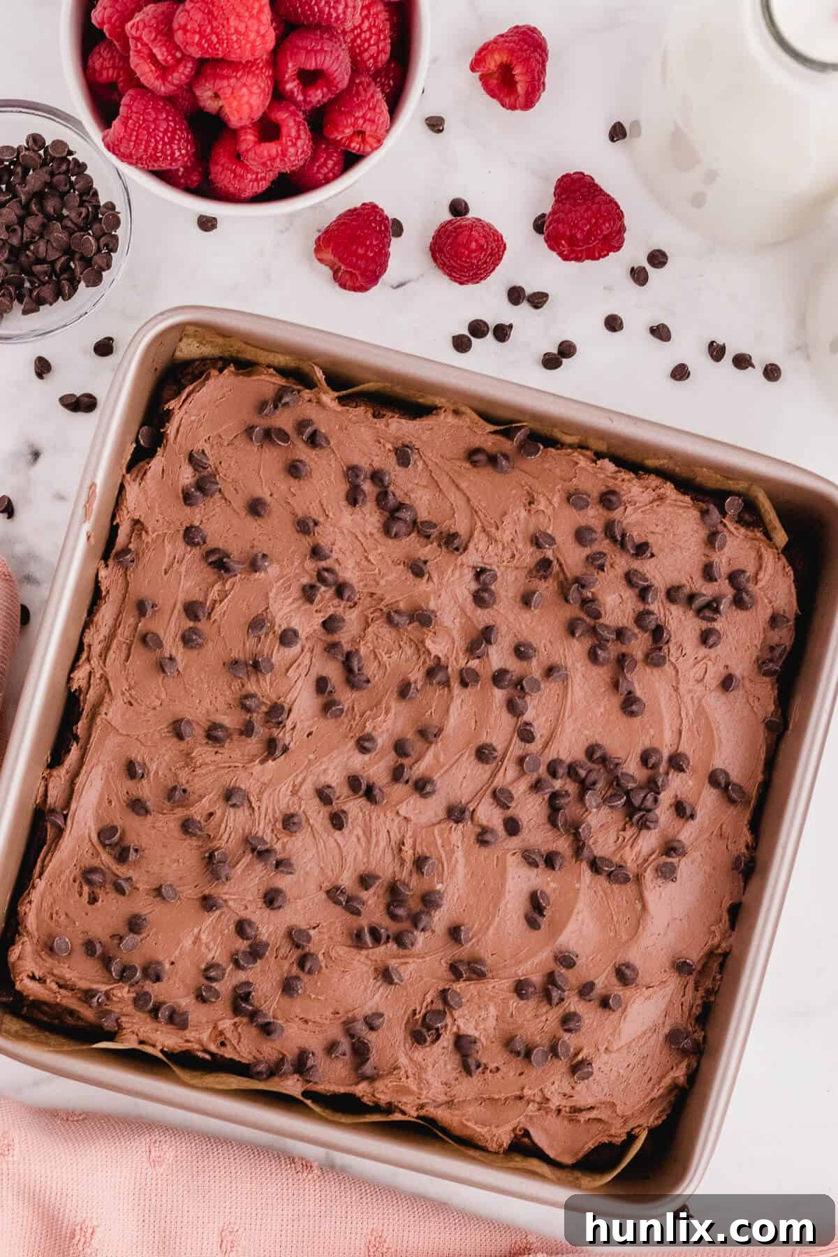 A pan of perfectly cut chocolate raspberry brownies, showcasing their fudgy texture and vibrant raspberry frosting.