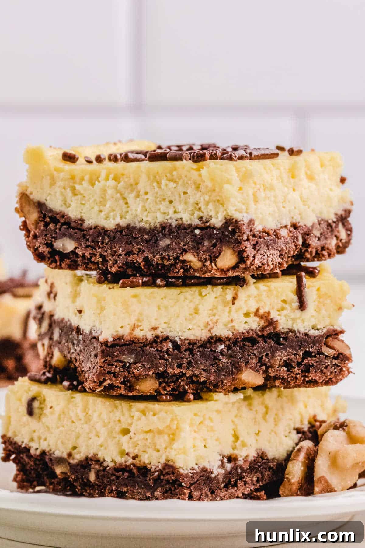 A stack of 3 cheesecake squares, showcasing the rich chocolate nut crust and creamy filling.