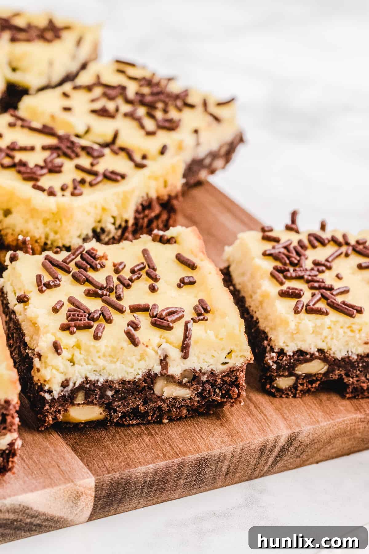Cheesecake squares arranged neatly on a wooden cutting board, ready for slicing.