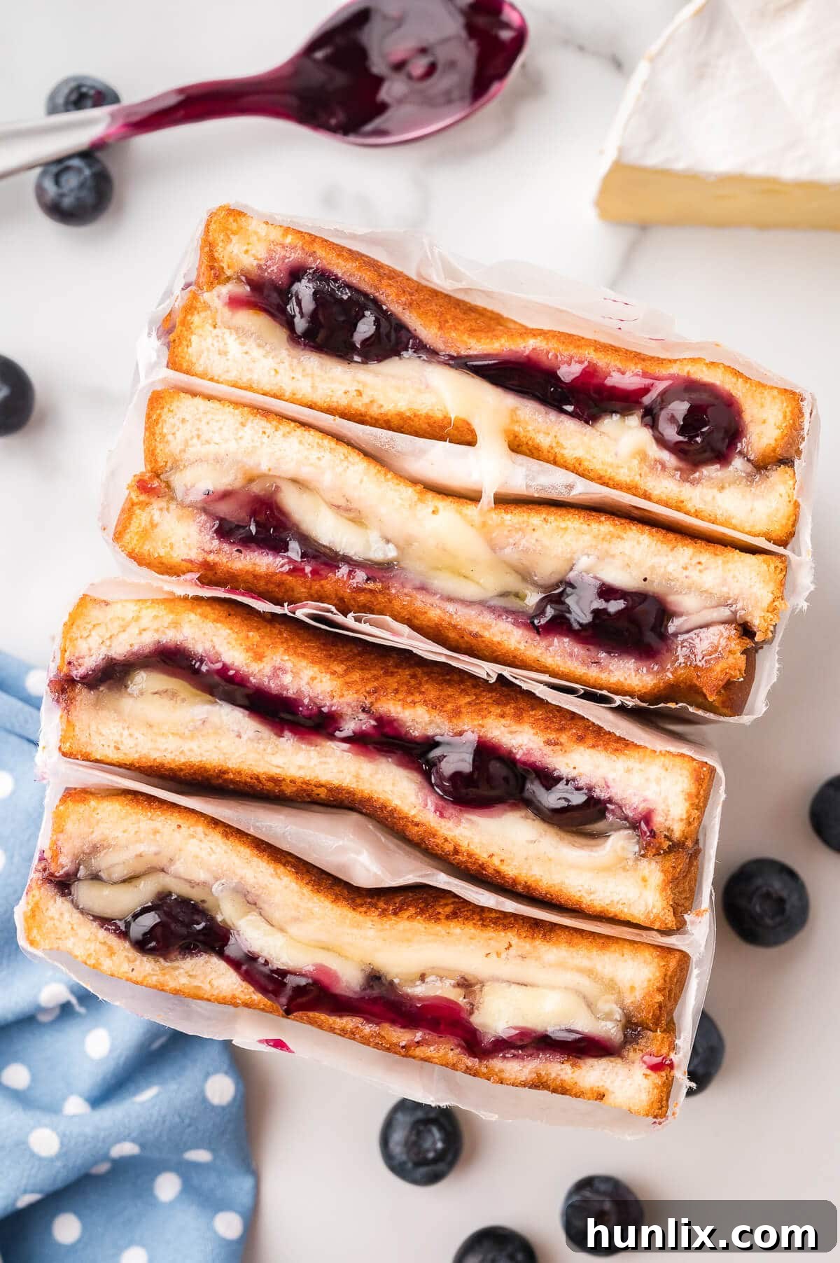 A blueberry brie grilled cheese wrapped in parchment paper, ready to be served.