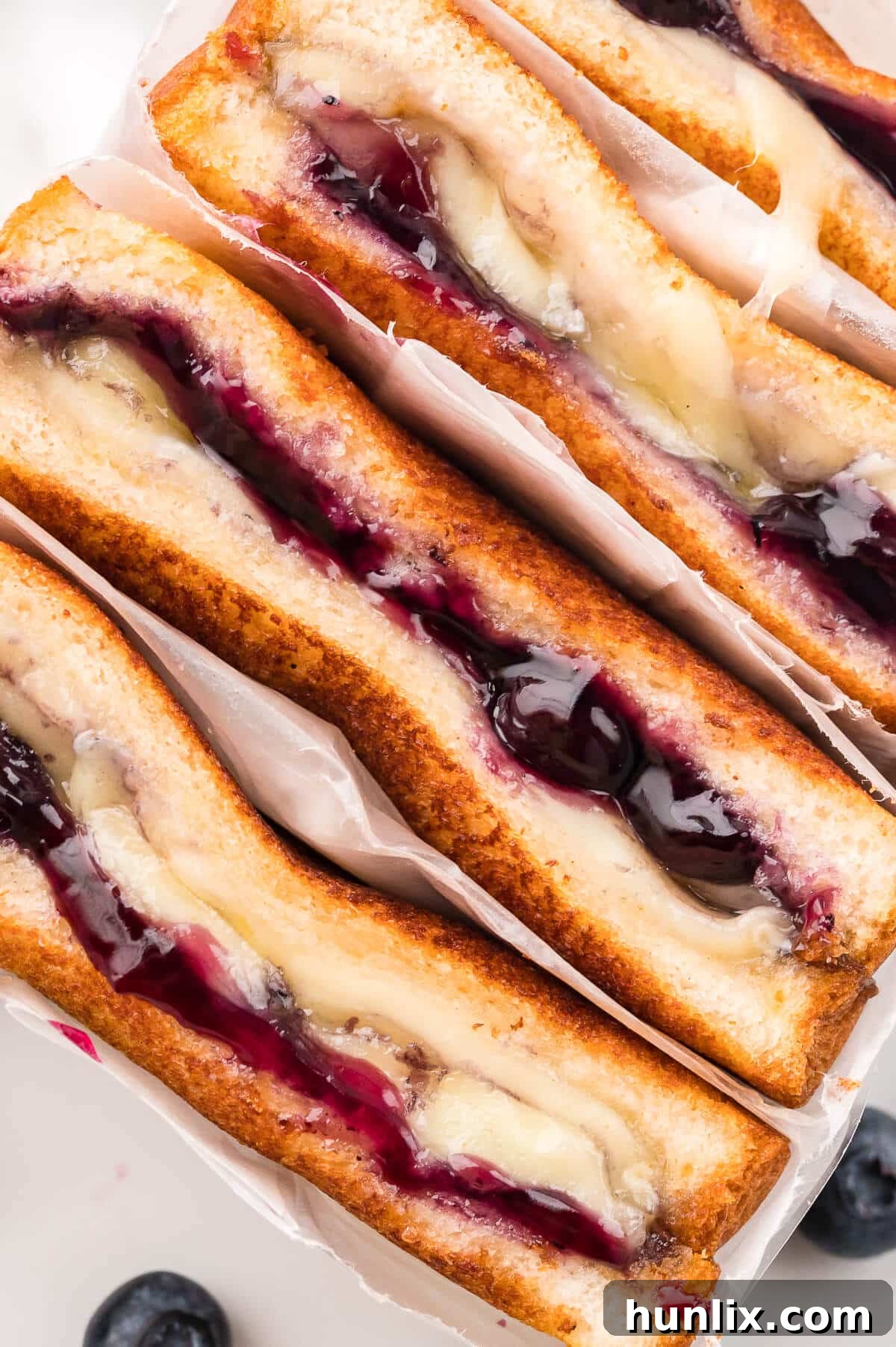 Close up of a blueberry brie grilled cheese sandwich, showing the melted brie and blueberry filling.
