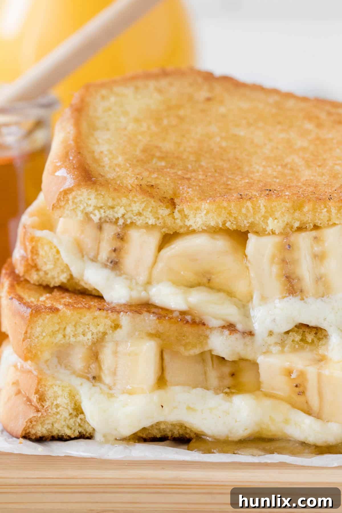 Two halves of a Honey Banana Grilled Cheese sandwich, showing the melted cheese and banana filling.