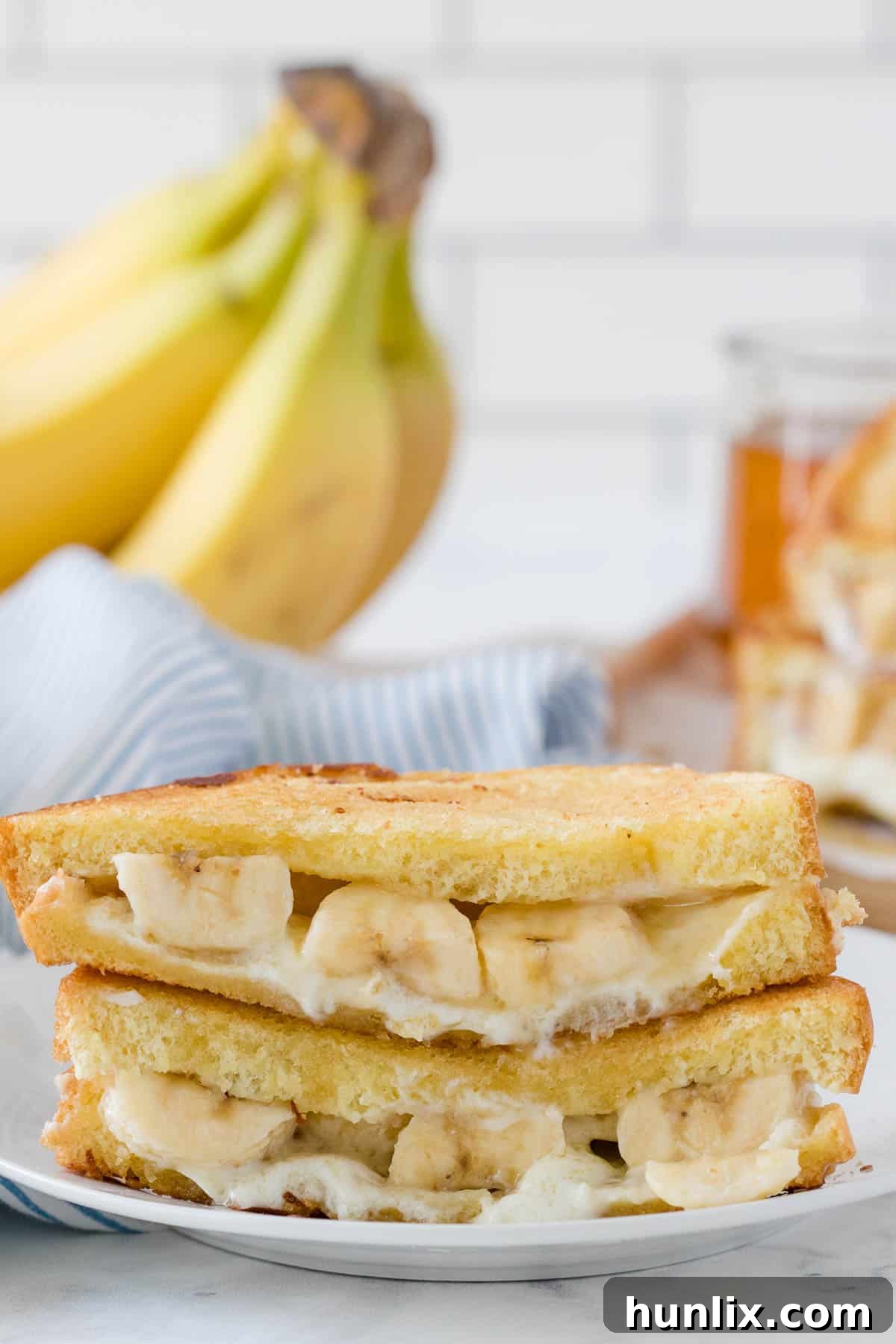 A single Honey Banana Grilled Cheese sandwich on a white plate, cut in half.