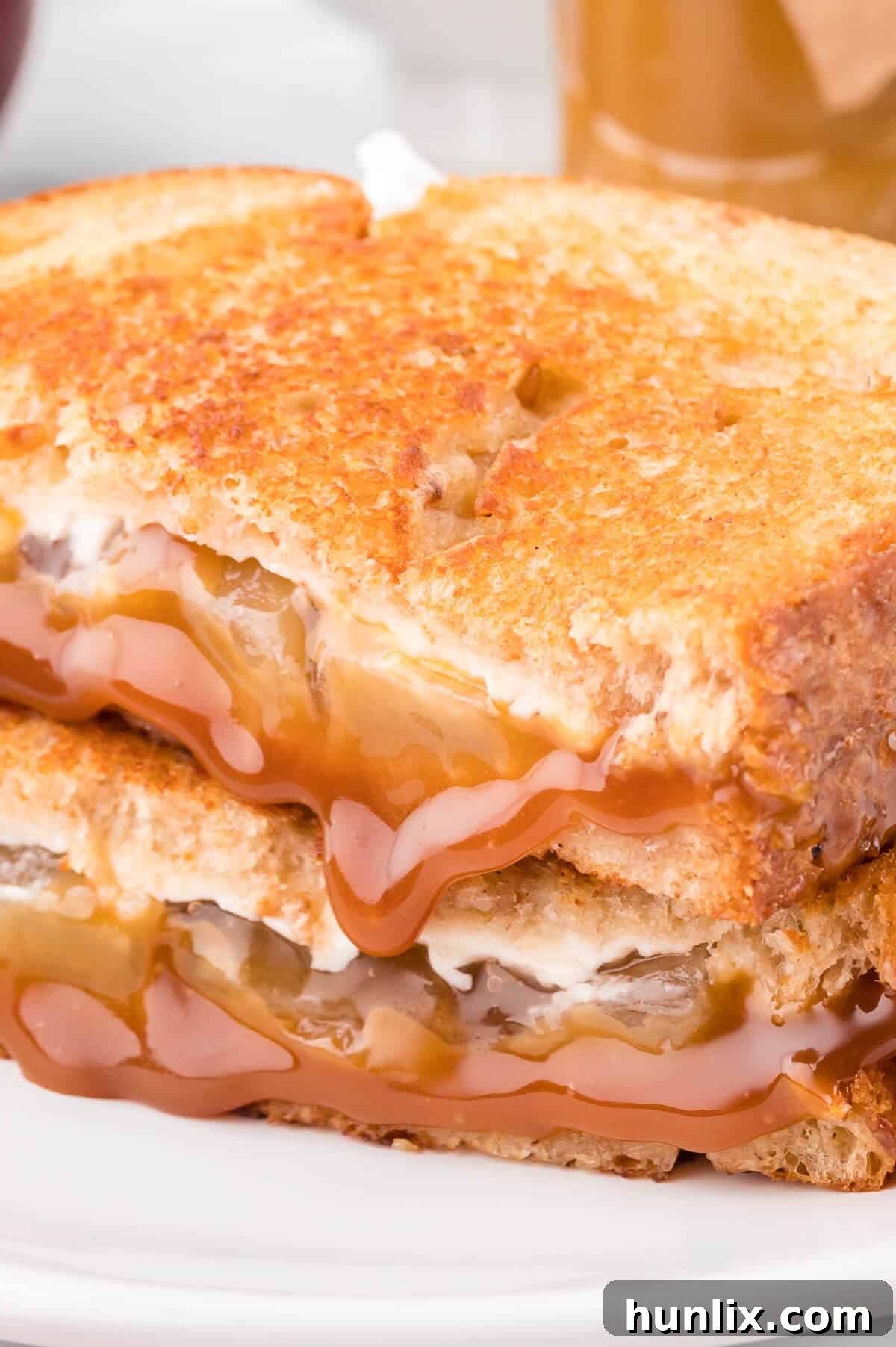 Sweet & Savory Caramel Apple Melt 8 A single caramel apple grilled cheese sandwich on a white plate, showcasing its golden crust and melted interior.