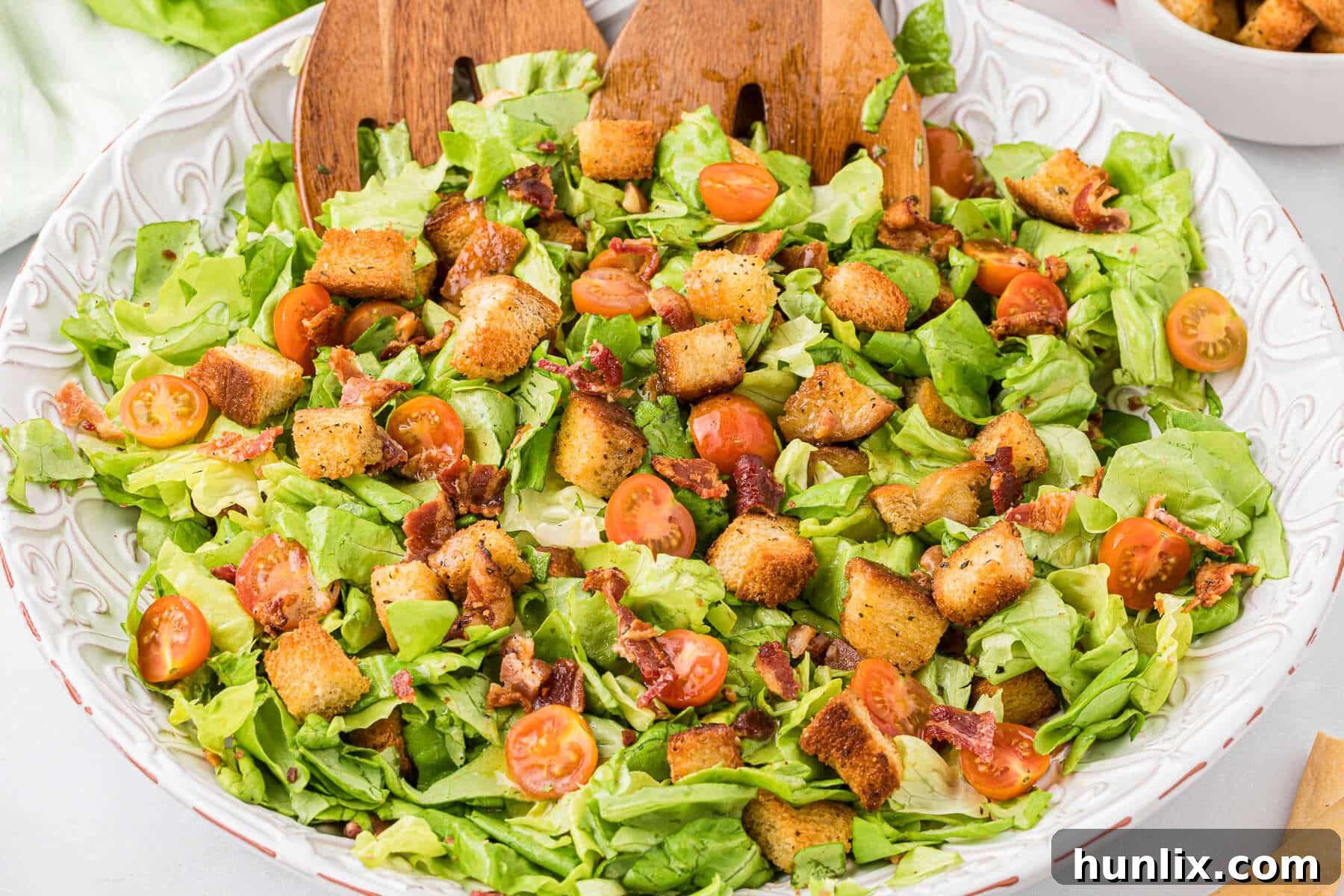 Deconstructed BLT Salad 7 BLT salad in a clear glass bowl with wooden salad tongs.