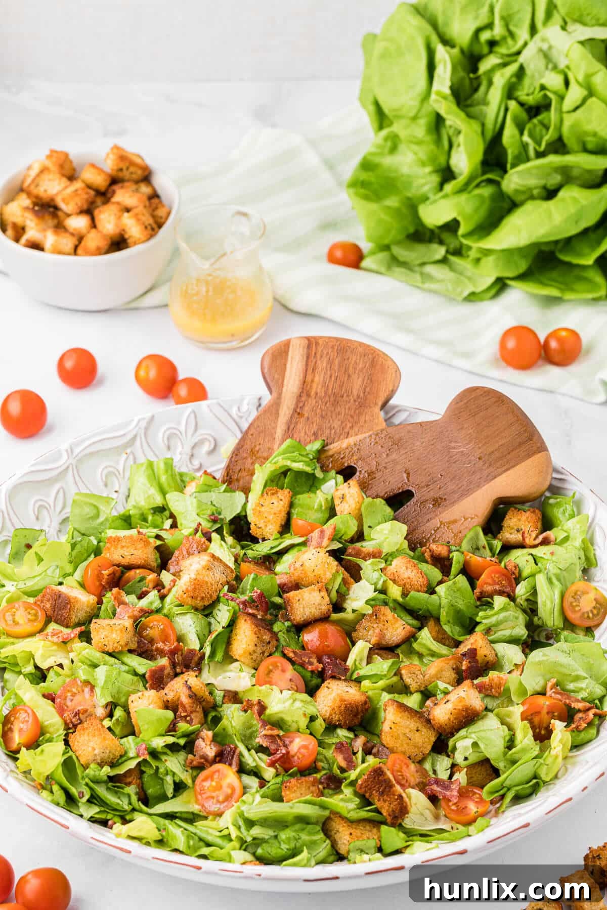 Deconstructed BLT Salad 8 BLT Salad in a white bowl with wooden salad tongs, close-up shot.