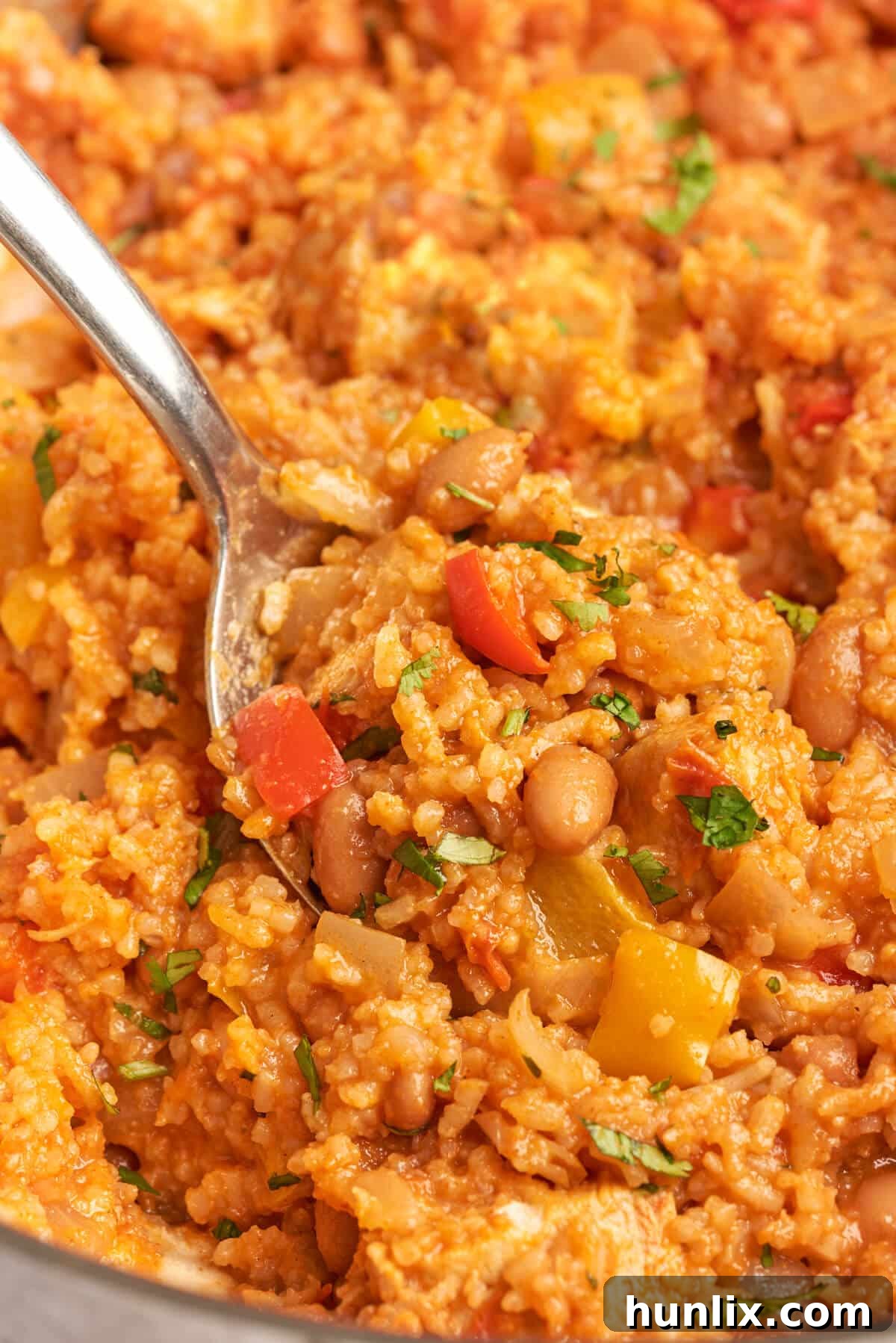 Skillet Chicken Burrito Fiesta 7 Serving spoon resting in a pot of freshly made one-pot chicken burrito bowl, steam rising.