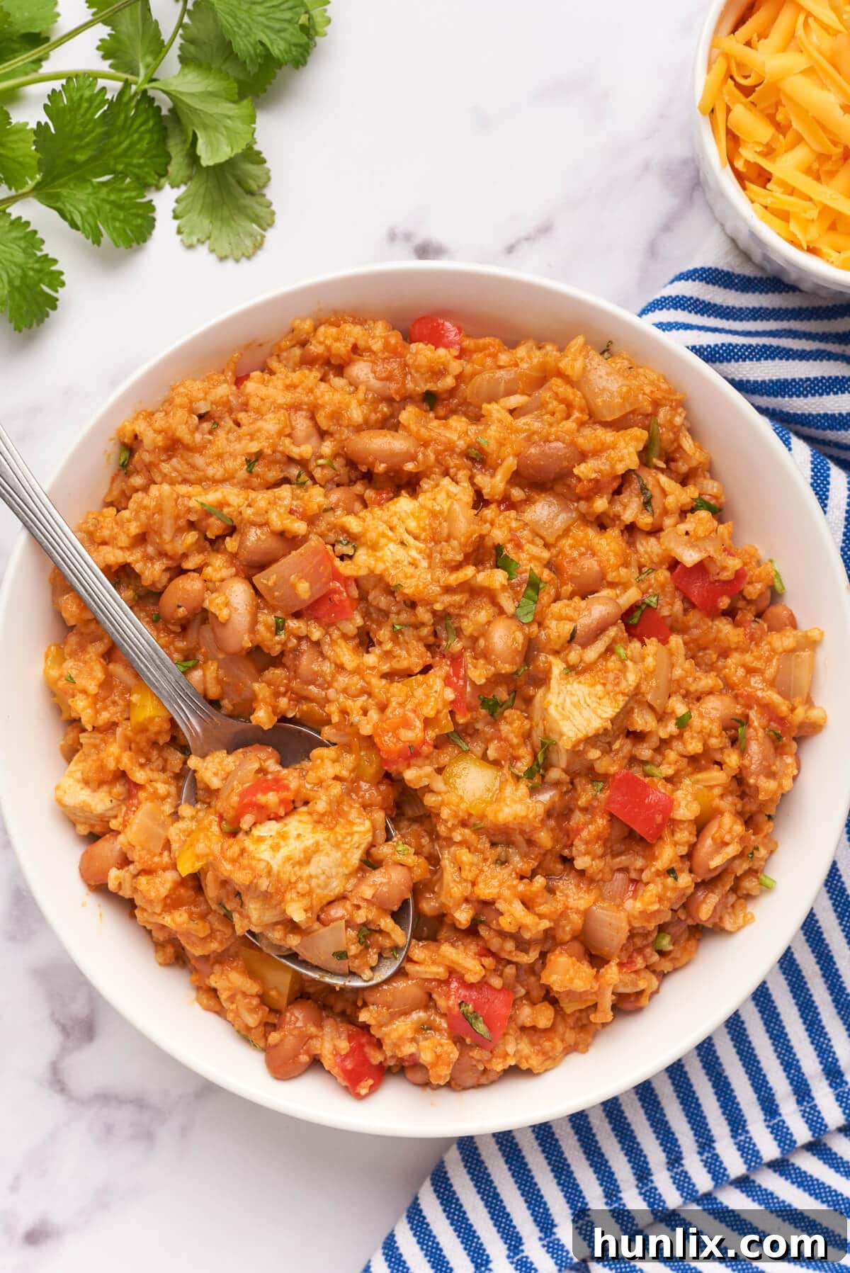 Skillet Chicken Burrito Fiesta 8 Single serving of chicken burrito bowl in a white bowl with a spoon, garnished with cilantro.