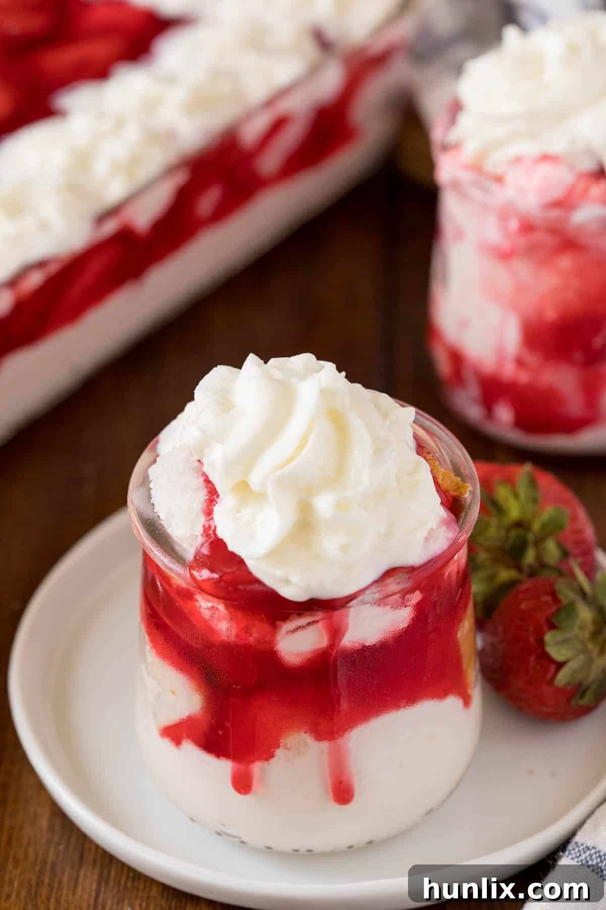 A serving of Strawberries in the Snow in a clear parfait dish, showing off the layers.