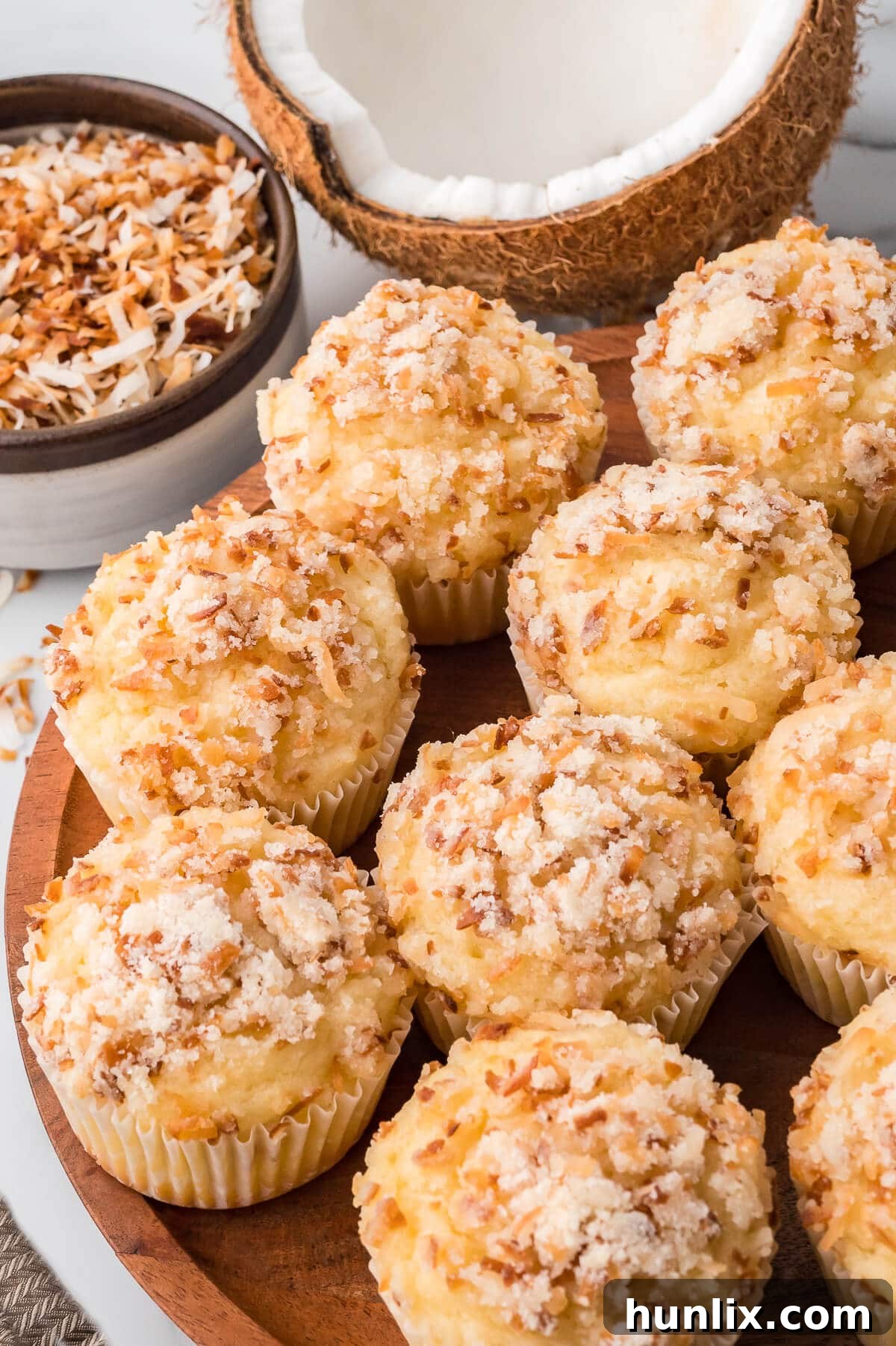 Toasted coconut muffins arranged beautifully on a rustic wooden platter.