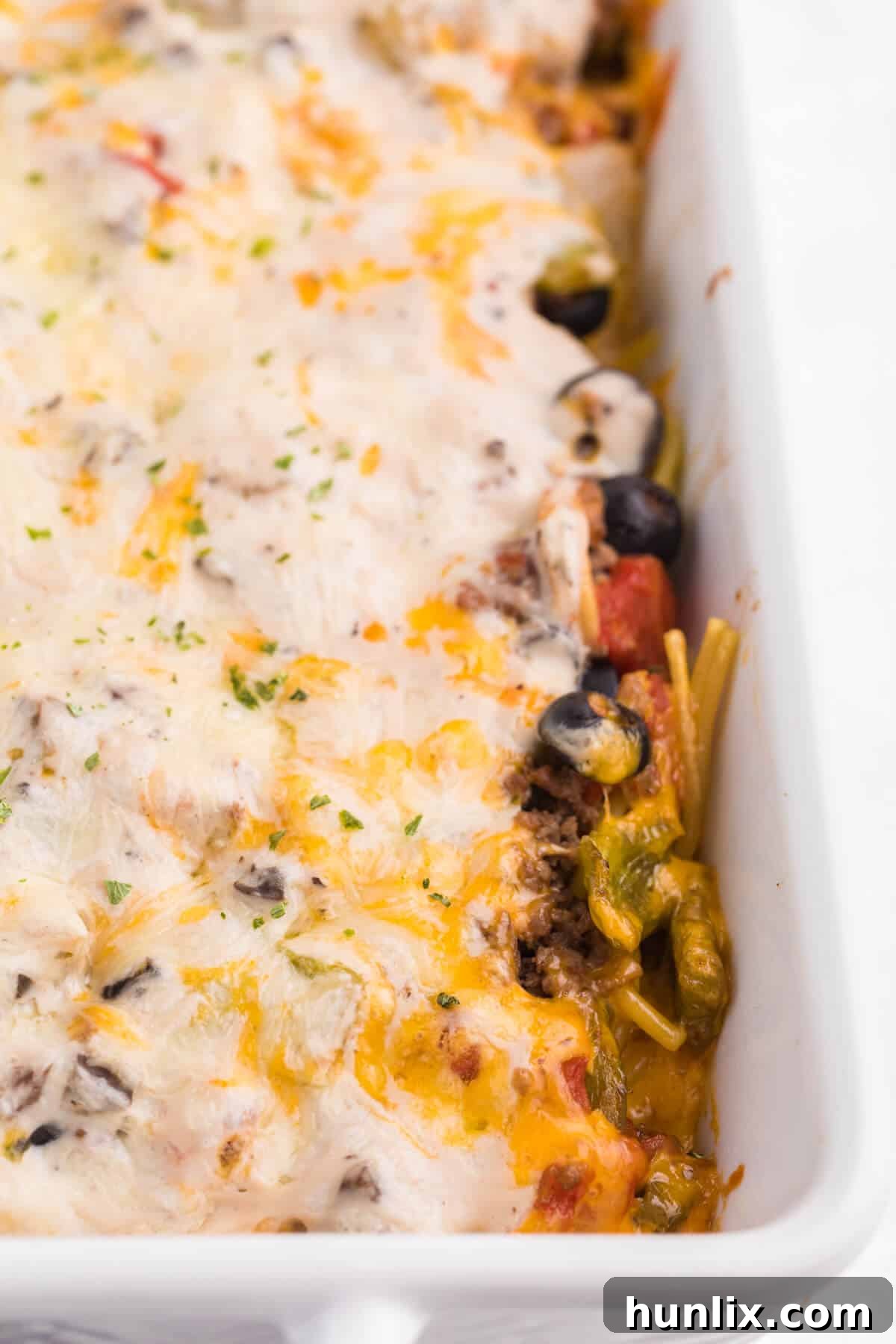 Hearty Spaghetti Bake 9 A large white casserole pan filled with a freshly baked spaghetti casserole, steam gently rising.