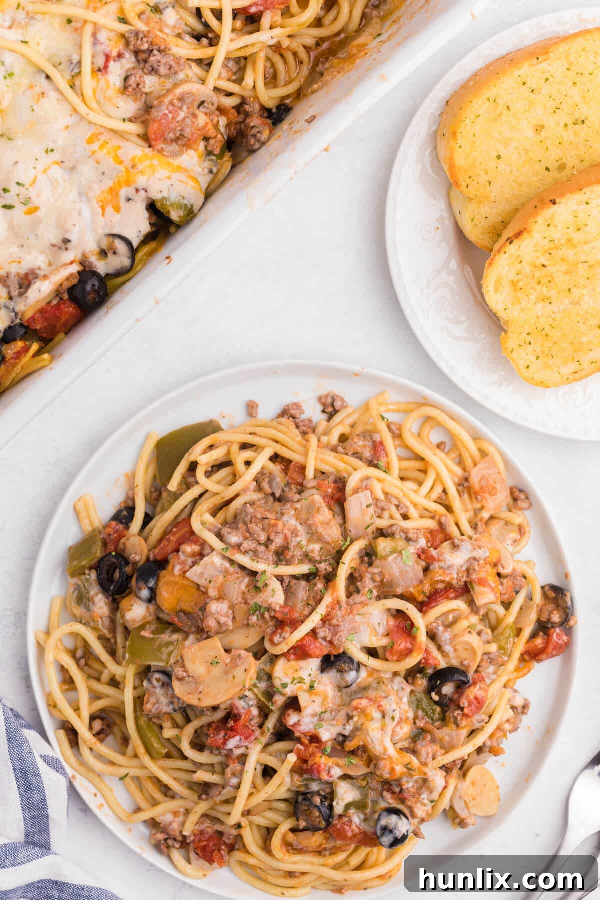 Hearty Spaghetti Bake 10 A generous serving of spaghetti casserole on a white plate, garnished with fresh parsley.
