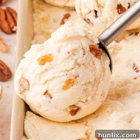 Maple pecan ice cream in a container with an ice cream scoop.