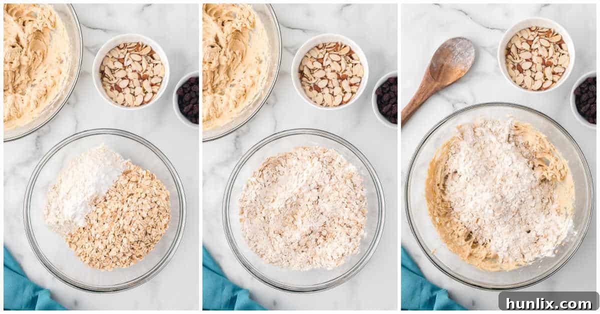 Hearty Trail Mix Oatmeal Cookies 6 Dry ingredients including flour and oats being gently stirred into the wet cookie dough mixture, showing the precise moment of combining the elements.