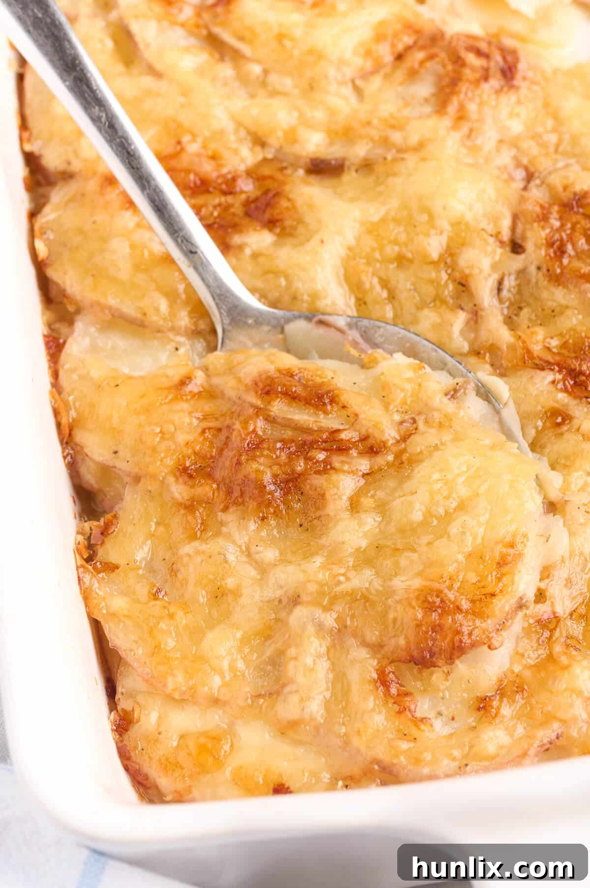 A serving spoon in a pan of Swiss Potatoes.
