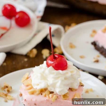 A slice of Banana Split Brownie on a white plate, showcasing the pink frosting and chocolate base.