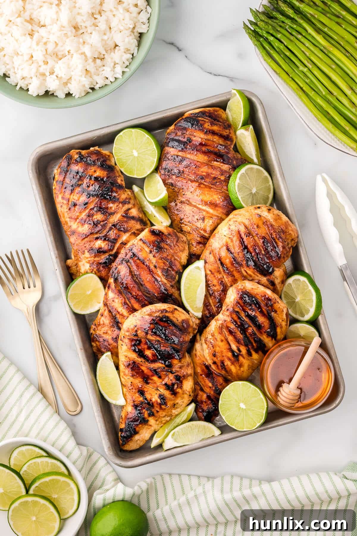 Ginger lime chicken on a platter with fresh lime slices and a drizzle of honey.
