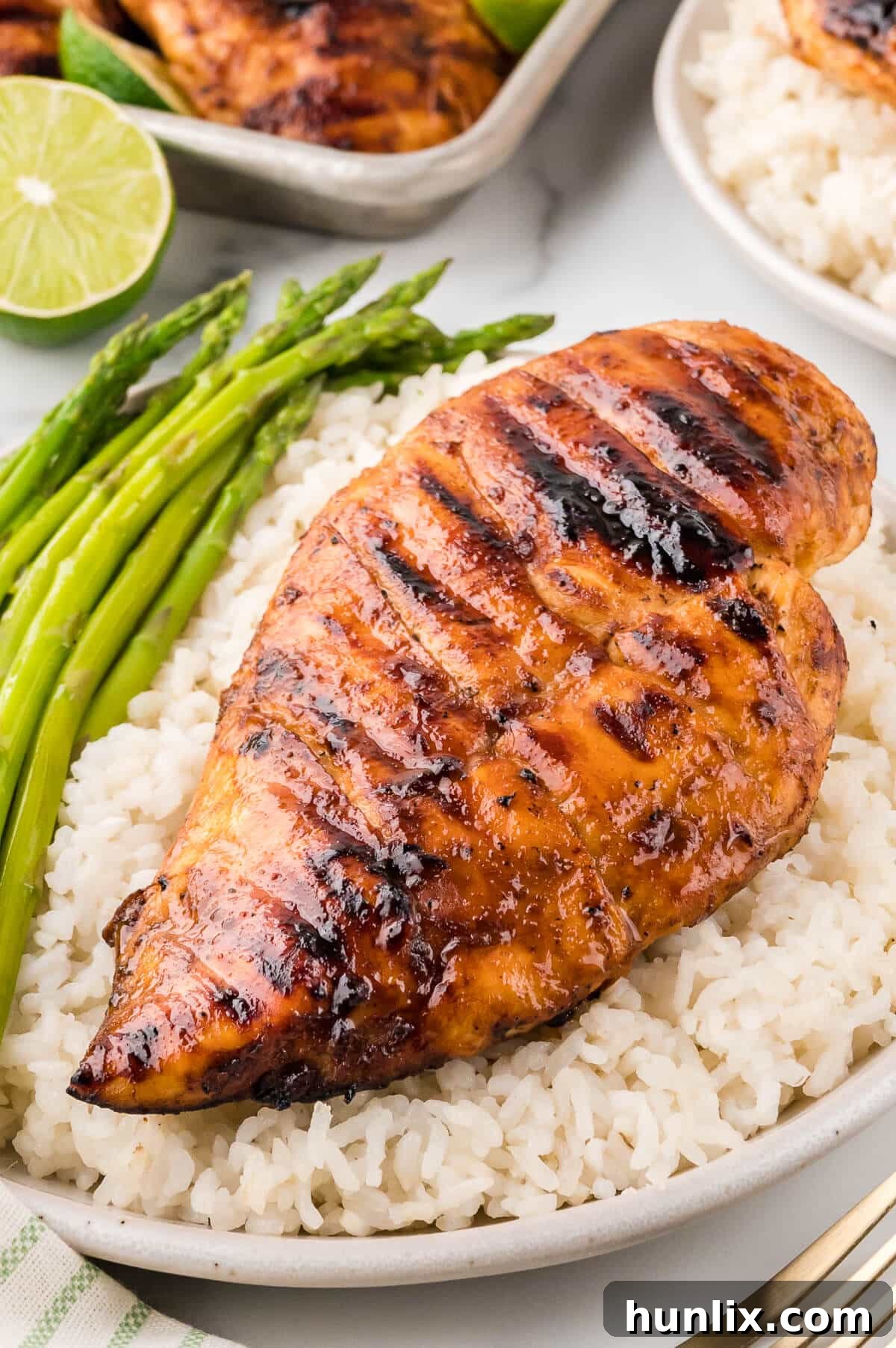 Ginger lime chicken on a bed of rice, served with grilled asparagus, and garnished with fresh lime.