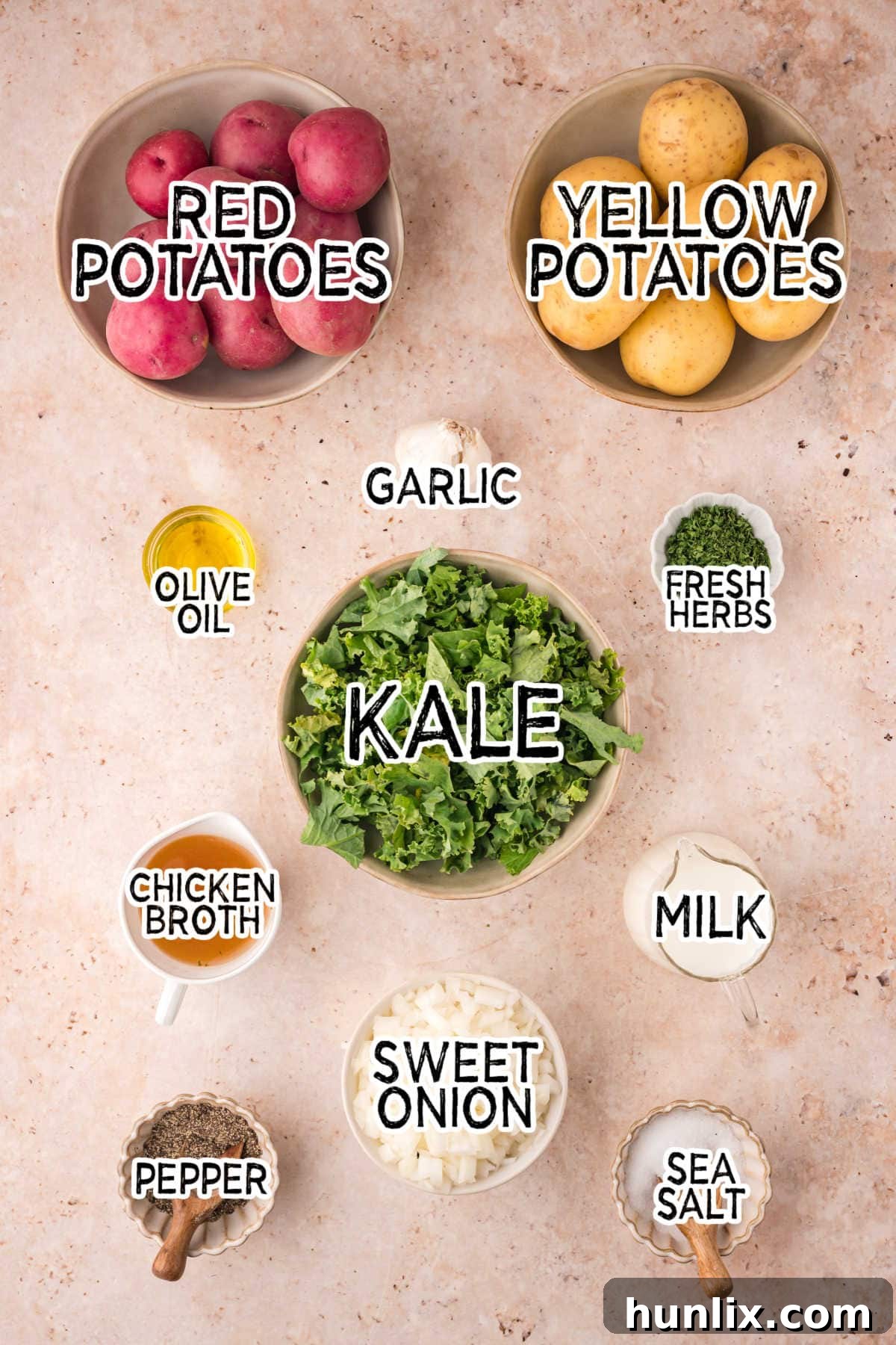 A flat lay photograph showcasing all the fresh ingredients needed for olive oil mashed potatoes with kale and herbs on a rustic brown surface.