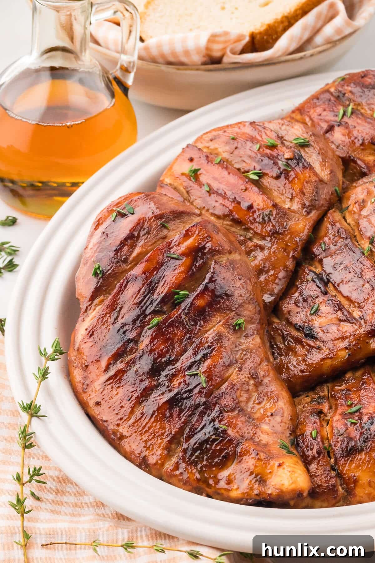 Grilled maple dijon chicken breasts arranged beautifully on a white platter, garnished with fresh herbs.