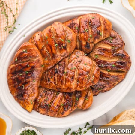 A group of chicken breasts on a white platter, ready to be served.