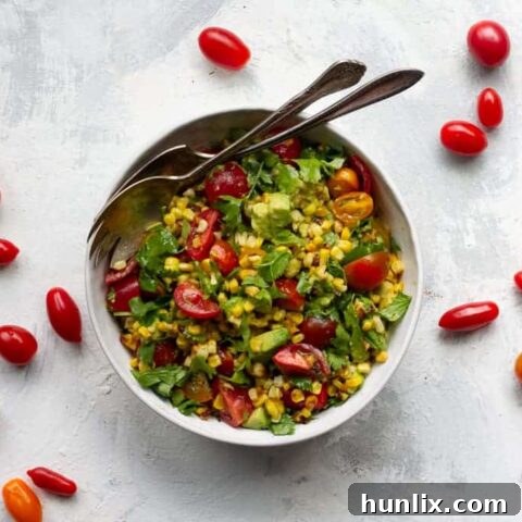 Fresh and easy tomato corn salad, a perfect summer side dish with roasted corn, ripe tomatoes, creamy avocado, aromatic herbs, and a simple vinaigrette.