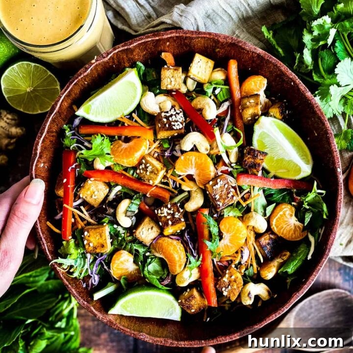 Bright and colorful Thai Salad topped with crunchy veggies, sweet mandarin slices, sesame-crusted tofu, and an Asian ginger dressing.